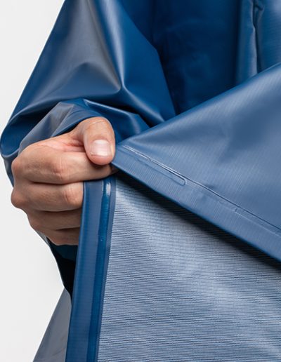 Close-up of a hand holding a blue waterproof poncho